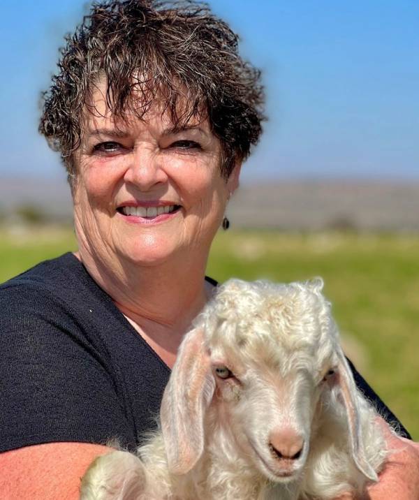 A woman holding a goat in her arms.