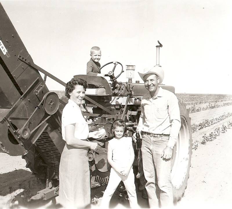 A family standing in front of an old tractor.
