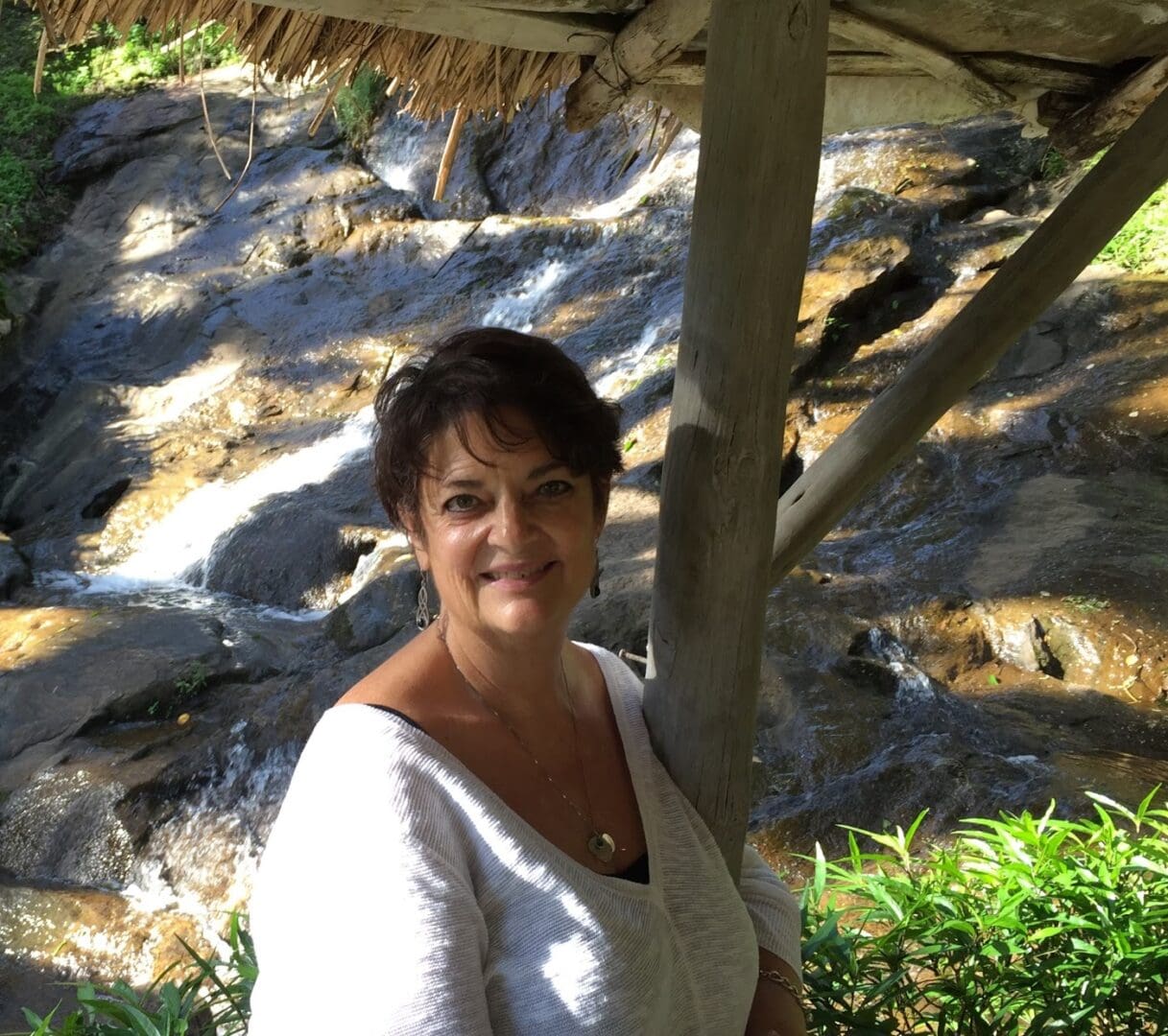 A woman standing under an umbrella in front of some rocks.