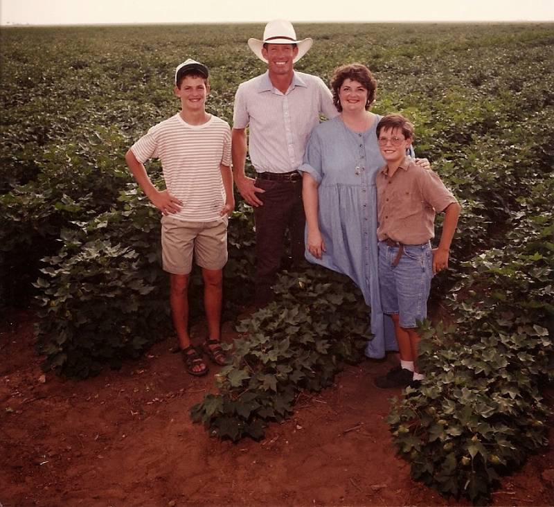 A family standing in the middle of an open field.
